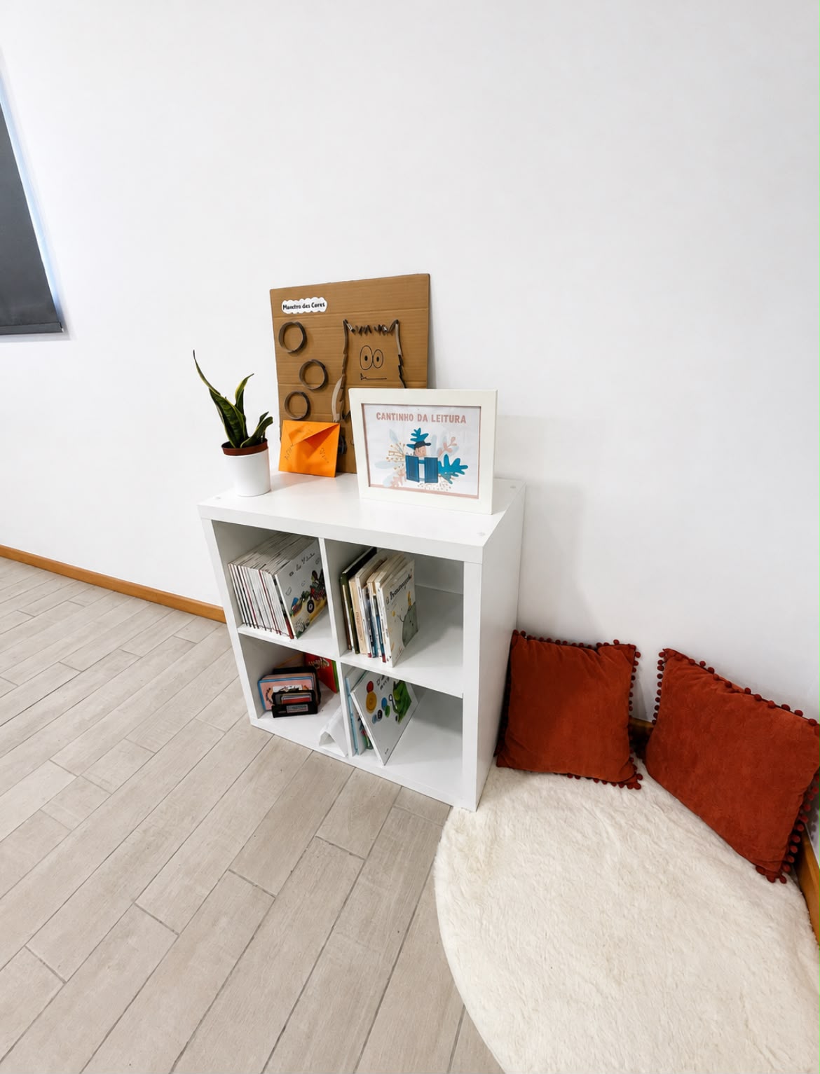 Cantinho de leitura do centro, com estante de livros, almofadas e tapete