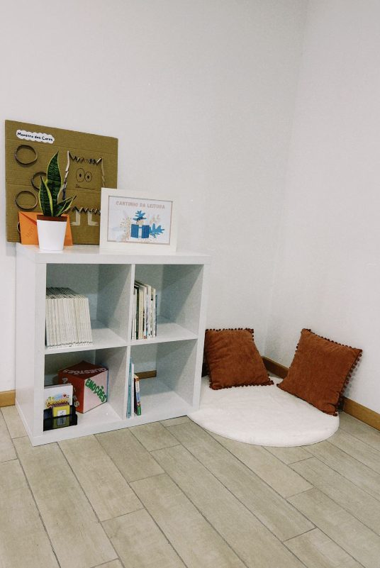 Cantinho de leitura, com estante de livros, almofadas e tapete